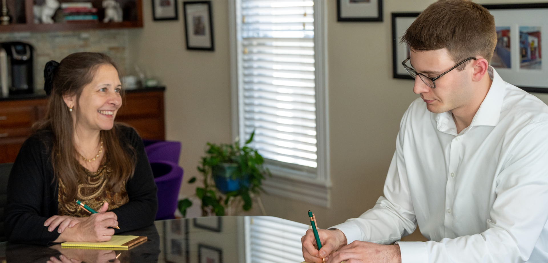 Derek Hess, CFP®, at a financial planning meeting with a woman, sitting at a conference room table.